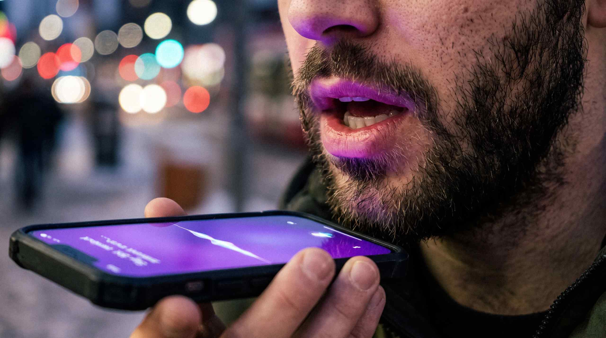 A closeup of a man talking to Siri on an iPhone